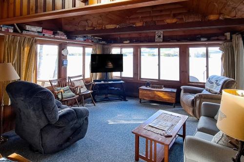 a living room with couches and a tv at Vintage lakefront cabin with incredible water views, private dock & pebble beach in The Highlands
