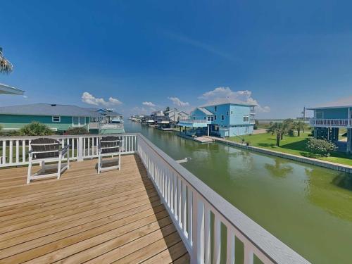two chairs sitting on a boardwalk next to a river at West Bay Getaway in Galveston