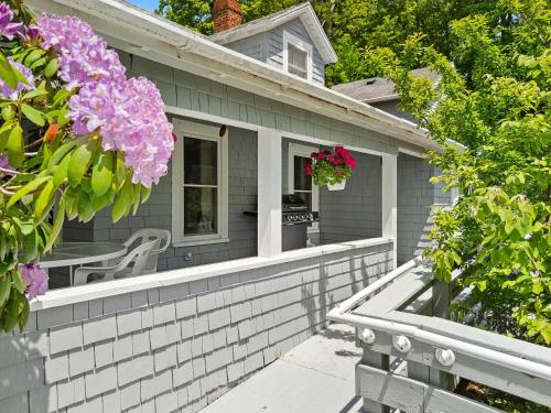 a gray house with a window and flowers at Bright, spacious getaway with full kitchen, furnished porch & WiFi - near trails in Seal Harbor