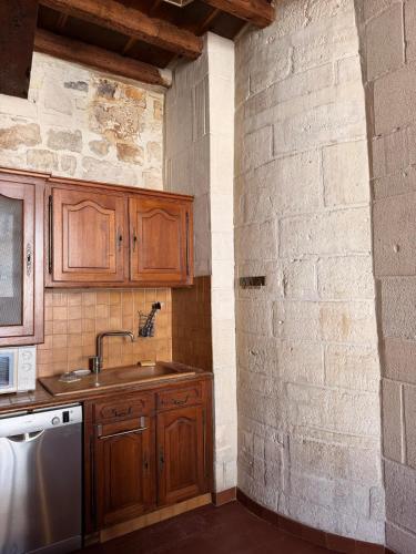 a kitchen with wooden cabinets and a sink at Les chambres de Pierre in Arles