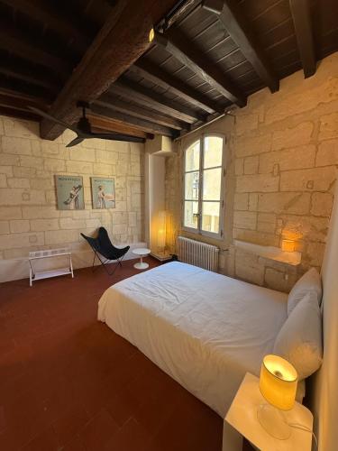 a bedroom with a large white bed and a chair at Les chambres de Pierre in Arles