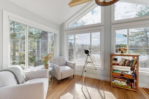 a living room with windows and a camera on a tripod at Charming cottage with a spacious deck overlooking the Megunticook River in Camden