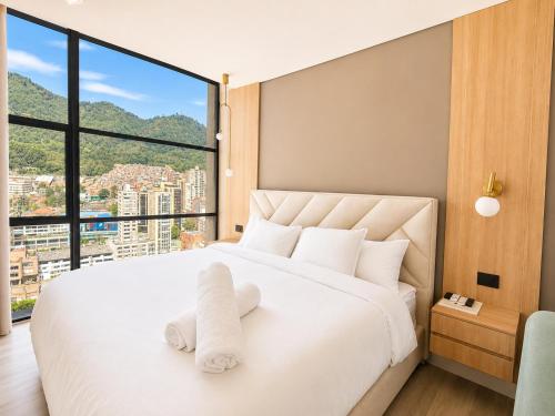 a bedroom with a white bed with a large window at Apartaestudio Centro Internacional UTEK in Bogotá