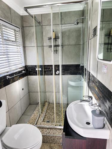 a bathroom with a shower and a toilet and a sink at Waterfall City Guest Lodge in Sandton
