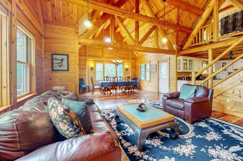 a living room with a leather couch and a table at Tranquil Haven | Secluded waterfront house with sauna, dock, kayaks, canoe, gym in Greenville