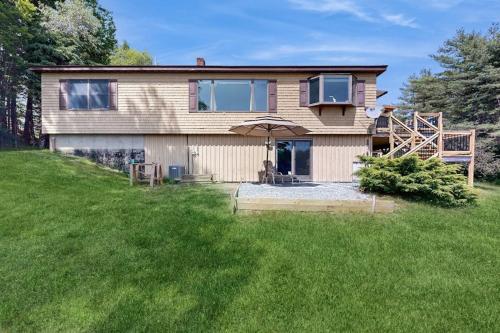 a house with an umbrella in a yard at Charming Lakefront House with Outdoor Firepit, Washer/Dryer and Wifi in Gouldsboro
