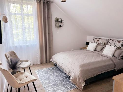 a bedroom with a bed and a chair and a window at Apartament Storczykowy in Frombork