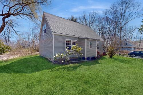 a small house in a yard with green grass at Dog-friendly home with deck, pool table, & firepit - walk to downtown Boothbay in Boothbay Harbor