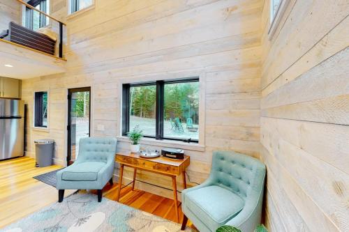 a living room with two chairs and a wooden wall at Contemporary retreat with grill, firepit, & patio - walk to beach in Marlboro