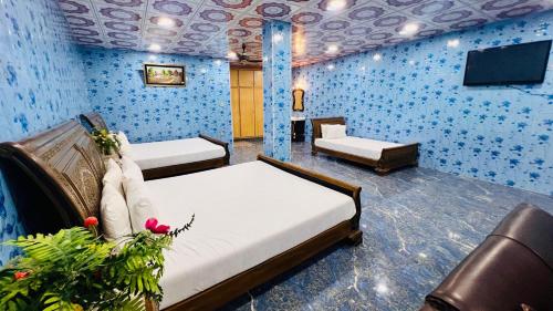 a room with two beds and a flat screen tv at The Al-Maaz Guest House in Murree