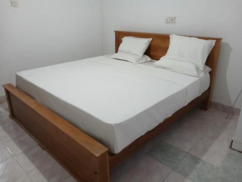 a bed with a wooden frame and white sheets and pillows at The Emerald Ceylon - Colombo in Pannipitiya