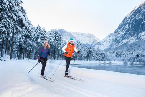 two people on skis in the snow next to a river at Forest Chalet, 15 min to salzburg olt town, and most beautiful lakes, secluded location, 1,000 sqm garden, mountainview, panorama sauna, bath whirlpool, BBQ&bikes&sunbeds for free, up to 10 p in Golling an der Salzach