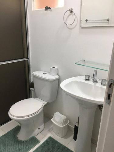 a white bathroom with a toilet and a sink at Private Suite with Kitchen & Pool Access in Itapetininga