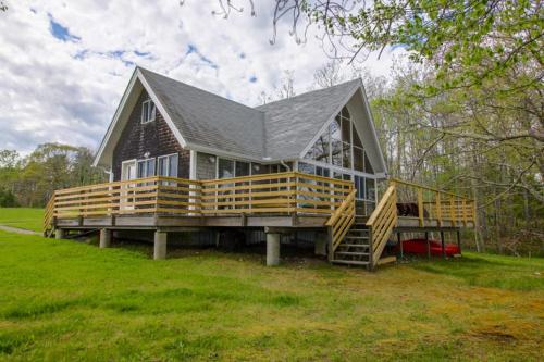 a large wooden house with a large deck at Remodeled Waterfront Home with Wraparound Deck, Water Views, & Beach Access in Waldoboro