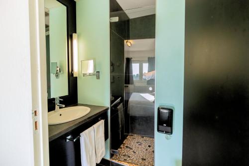 a bathroom with a sink and a mirror and a tub at Logis Clair Matin Resort & Spa in Le Chambon-sur-Lignon