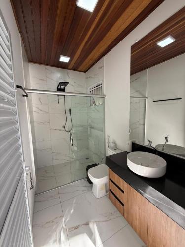 a bathroom with a glass shower and a sink at Casa Pé da Serra in Estivado