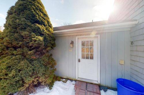a house with a white door next to a tree at Colorful duplex home with a large yard, deck, WiFi, & ideal Midcoast location in Boothbay