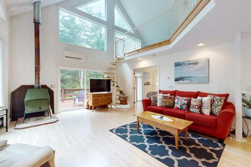 a living room with a red couch and a tv at Sunny coastal retreat with deck, grill, beach, dock, & ocean access in East Boothbay