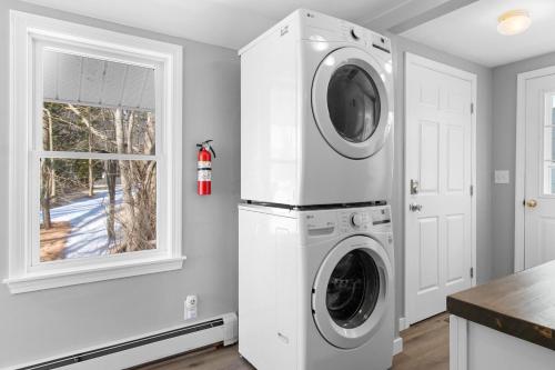 a white laundry room with a washer and dryer at Cobbossee Hideaway, lakefront property with dock for swimming, fishing, and sunrises in Winthrop