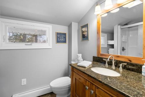 a bathroom with a sink and a toilet and a mirror at Cobbossee Hideaway, lakefront property with dock for swimming, fishing, and sunrises in Winthrop