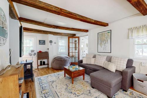 a living room with a couch and a table at Charming Boothbay Harbor cottage with partial AC, full kitchen, and sun room in Boothbay Harbor