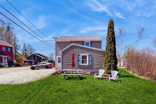a house with two chairs and a table and a tree at Well-located, dog-friendly home - walk to footbridge & Barrett Park in Boothbay Harbor