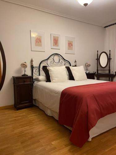a bedroom with a large bed with a red blanket at La Casita de Numancia in Garray