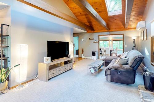 a living room with a couch and a flat screen tv at Tree-lined home with screened porch & perfect Midcoast location in Damariscotta