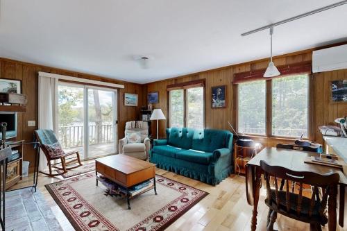 a living room with a blue couch and a table at Lady Slipper Cottage: Charming Lakefront Retreat with Canoes, Kayaks, and Modern Comforts in Somesville