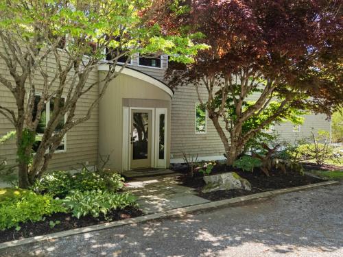 a house with trees in front of it at Elegant ocean view home with breathtaking views, private hot tub & large deck in Rockport
