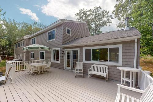 a house with a deck with a table and chairs at Waterfront home with deck, patio, grill, firepit, Ping-Pong, & WiFi in Somesville