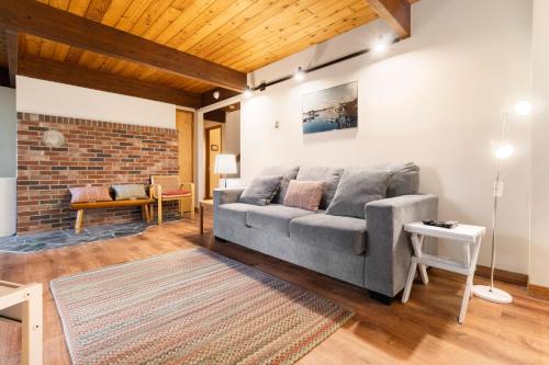 a living room with a gray couch and a brick wall at Beautiful hidden Waterfront Retreat with Rocky Beach in Boothbay