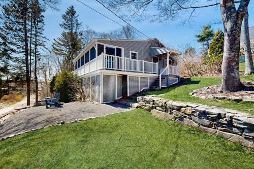 a large white house with a stone wall at Dog-friendly river-view home with wood stove, deck, patio, dock, beach, grill in Boothbay