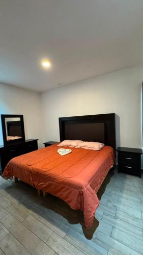 a bedroom with a bed with an orange bedspread at Departamento moderno en Durango in Durango