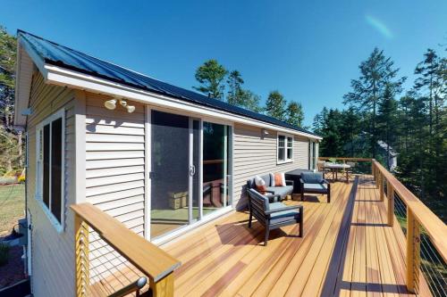 a large deck with chairs and furniture on a house at Newly-built waterfront home with fast WiFi, furnished deck, & washer/dryer in Waldoboro