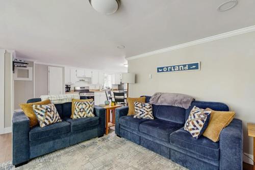 a living room with two blue couches and a kitchen at Secluded waterfront home with private dock, outdoor dining, firepit, WiFi & W/D in Orland