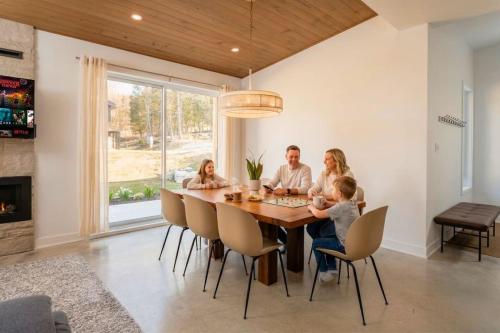 a family sitting around a dining room table at Chalet Gratitude with Private SPA & Sauna in Saint Come