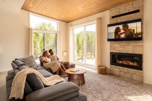 a group of people sitting in a living room with a fireplace at Chalet Gratitude with Private SPA & Sauna in Saint Come