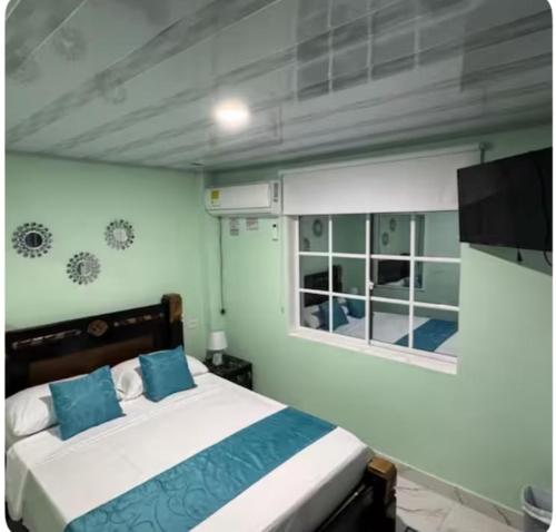 a bedroom with a bed with blue pillows and a window at Posada MaiMai in Providencia