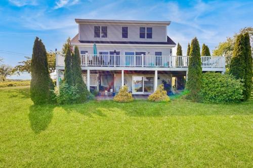 a large house with a large yard with trees at Oceanfront home with dock, beautiful deck & firepit - steps to the beach in Harpswell Center