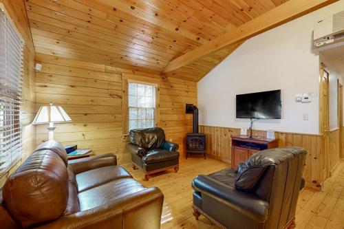 a living room with leather furniture and a flat screen tv at Comfortable two bedroom cabin with firepit, kitchen, hiking trail within walking in Northport