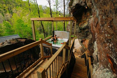 a person in a hot tub on a wooden deck at Cliff Hot Tub with Deck Fire Pit Mural and Pet Friendly in Rogers