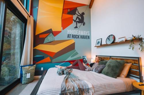 a woman laying on a bed in a room at Cliff Hot Tub with Deck Fire Pit Mural and Pet Friendly in Rogers