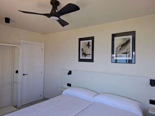 a bedroom with a white bed and a ceiling fan at Apartamentos Zenit Mar in Noja