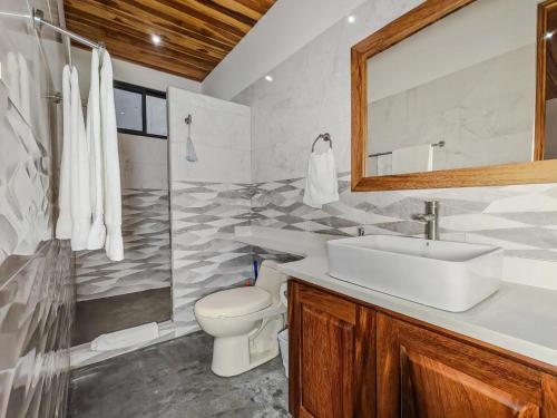 a bathroom with a sink and a toilet and a mirror at Samara by the River Vacation Suites in Sámara