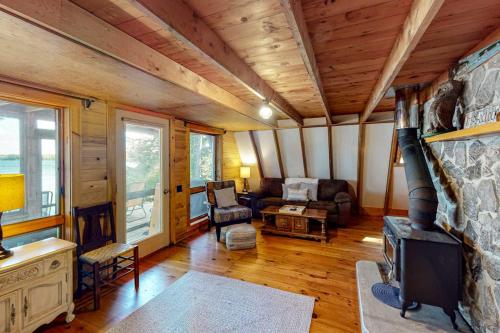a living room with a stone fireplace in a cabin at Waterfront A-frame on George's Pond with views, private dock, beach, kayaks, SUP in Franklin