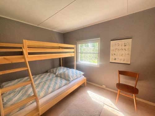 a bedroom with a bunk bed and a chair at Stuga Haget in Bengtsfors