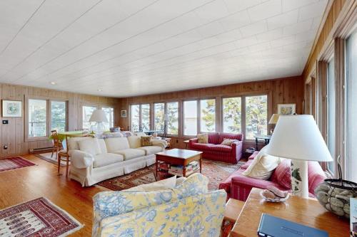 a living room with couches and tables and windows at Beachfront Delight with detached guesthouse, private beach access, Dog-friendly in Southport