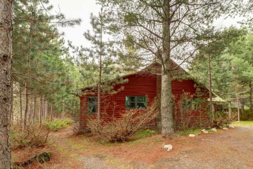 a red cabin in the middle of a forest at Lakefront Home with Private Dock, Pebble Beach & Enclosed Porch - Dogs Welcome in Greenville Junction