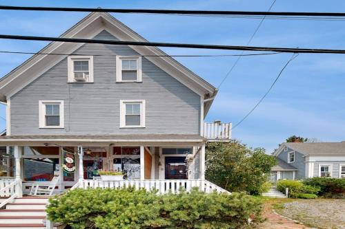 a gray house with a white porch and stairs at Charming, historic cottage with modern upgrades - stroll to dining & attractions in Boothbay Harbor